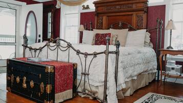 Un dormitorio clásico con una cama con dosel, un baúl antiguo y un espejo grande.