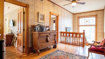 A room with wooden flooring, a large mirror, a ceiling fan, and a wooden railing.