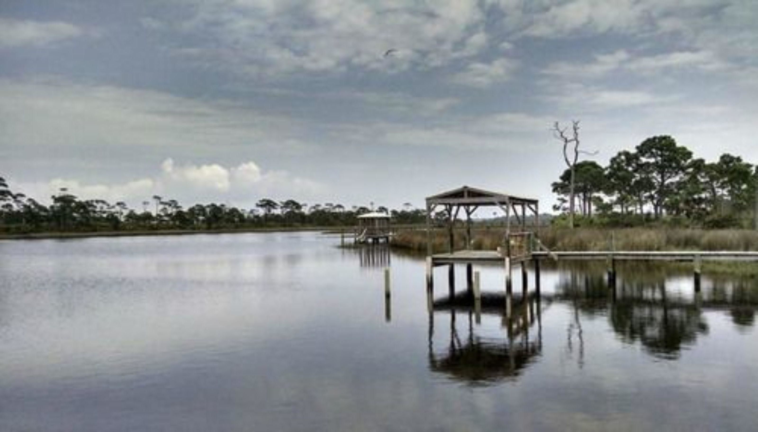Un lago tranquilo con un muelle de madera y un pabellón cubierto.
