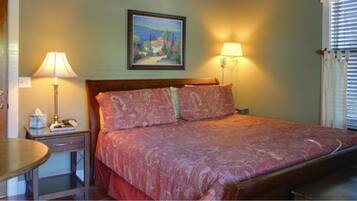 A bedroom with a bed, bedside lamps, a painting on the wall, and a window with blinds.