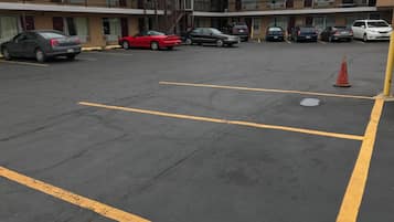 A parking lot with multiple cars parked in front of a motel with a two-story building and balconies.
