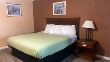 A single bed with a wooden headboard in a room with brown walls and two framed pictures.