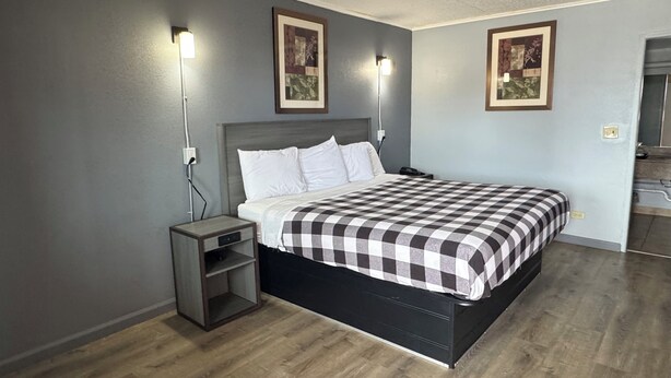A bedroom with a bed, nightstands, and wall-mounted lights. - Travel Inn (Broadview)
