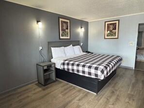 A bedroom with a bed, nightstands, and wall-mounted lights. - Travel Inn (Broadview)