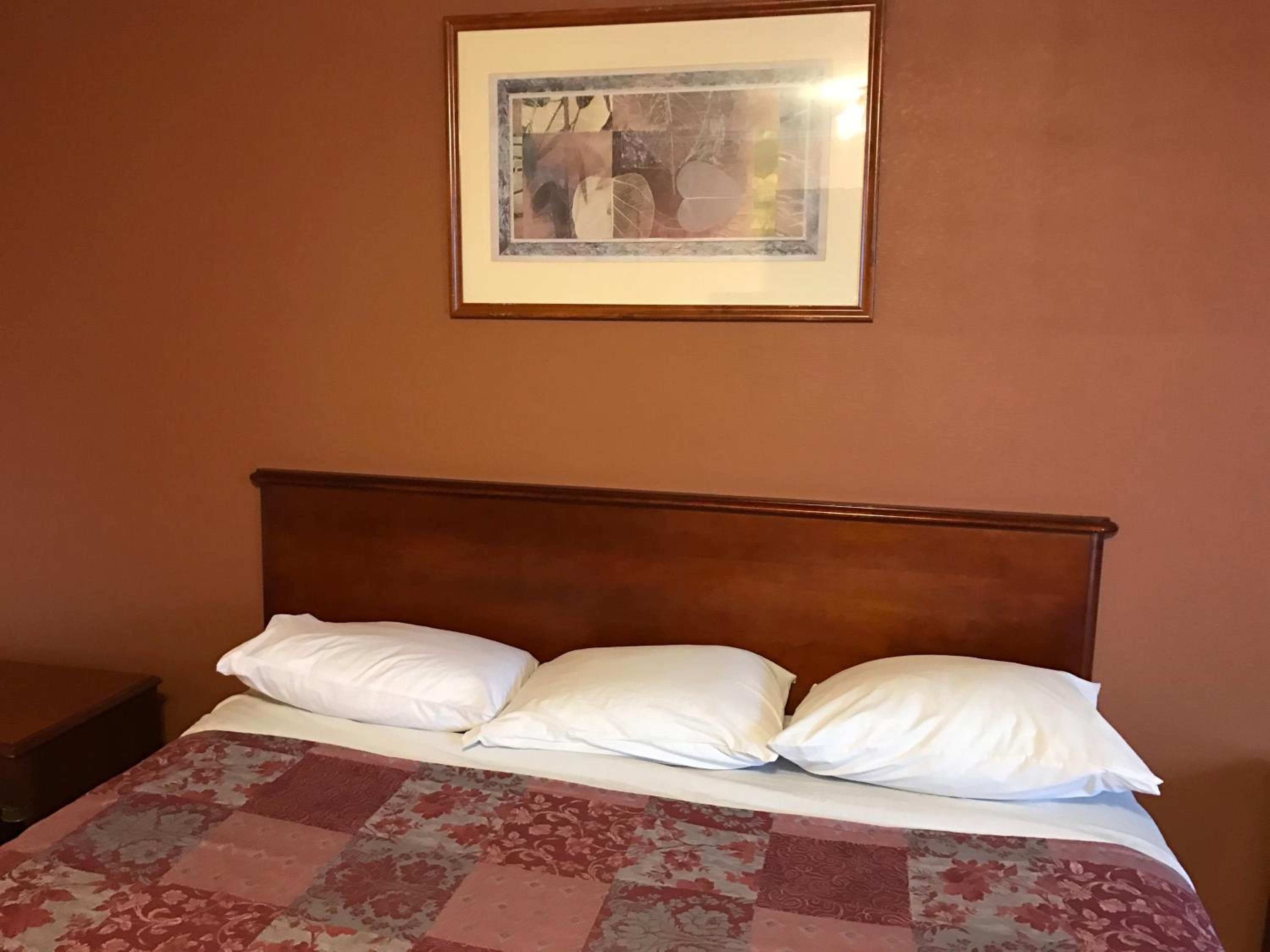 A bed with a wooden headboard, white pillows, and a floral-patterned bedspread.