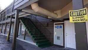 A building with a caution sign warning of a slippery floor when wet, a staircase, and a door labeled "ICE".