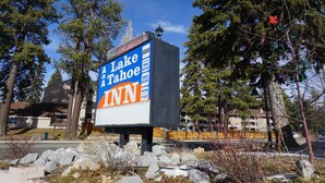 A billboard for Lake Tahoe Inn with a clear view of the surrounding area including trees and a building in the background.