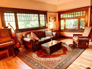 A cozy living room with a piano, a sofa, a chair, and a coffee table.