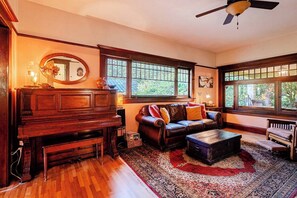 Una sala acogedora con un piano, un sofá de cuero y un tapete grande.