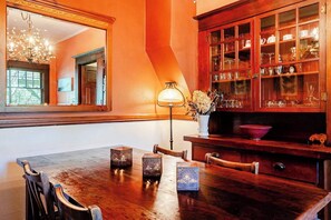 A dining area with a wooden table, chairs, a chandelier, and a cabinet with glass doors.