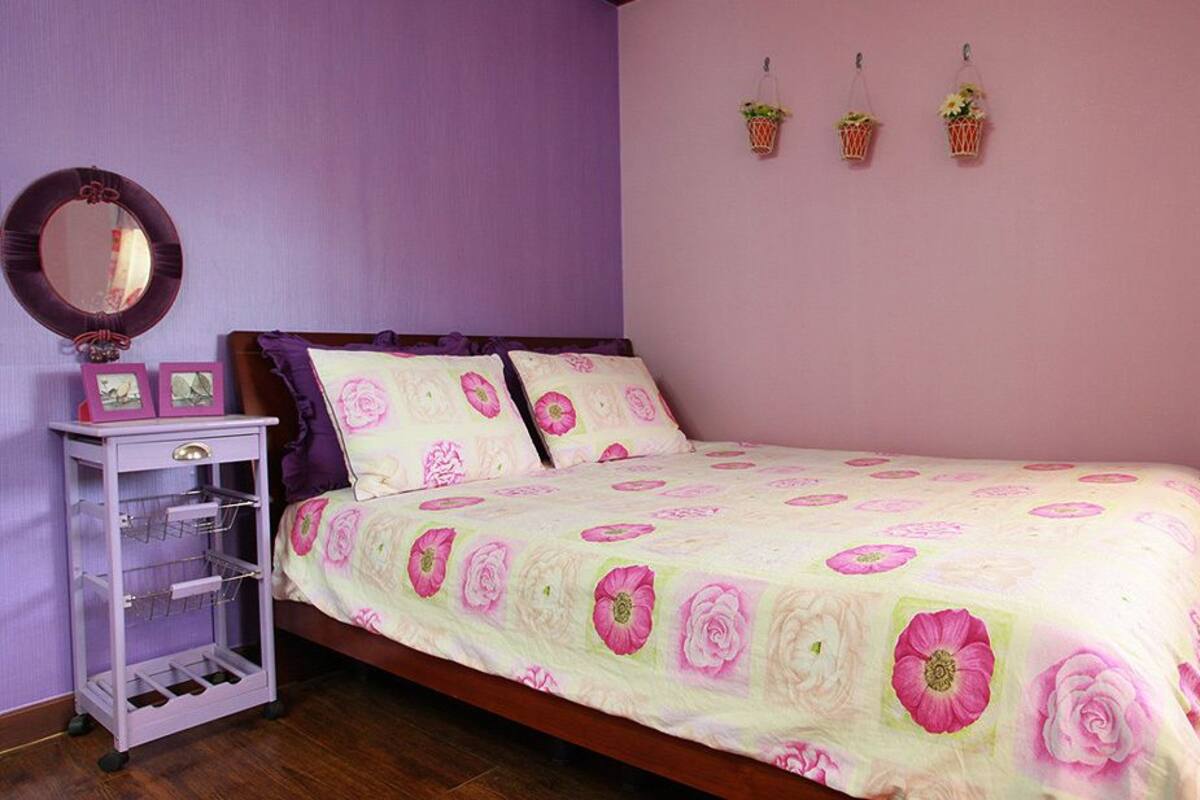 Un dormitorio con cama, cómoda, espejo y tres cestas fijadas a la pared.