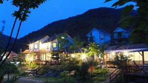 A row of houses with a well-maintained garden and a mountain backdrop. - Duo Pension (Pyeongchang)
