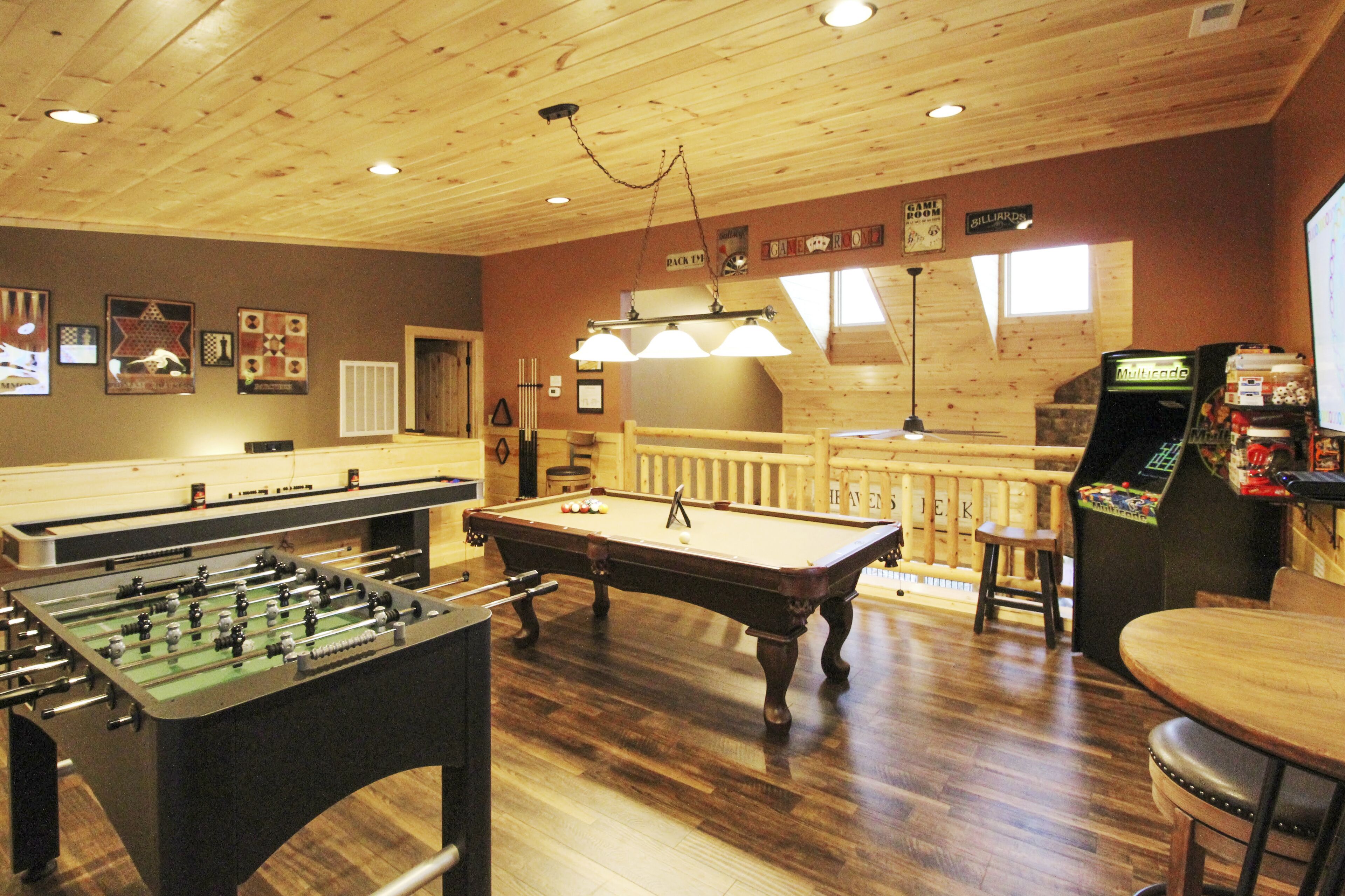 Una sala de billar con mesa de billar, mesa de fútbol de mesa y zona de bar con mesa de billar y juegos de arcade.