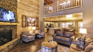 A spacious living room with a fireplace, comfortable seating, a dining area, and a kitchen.