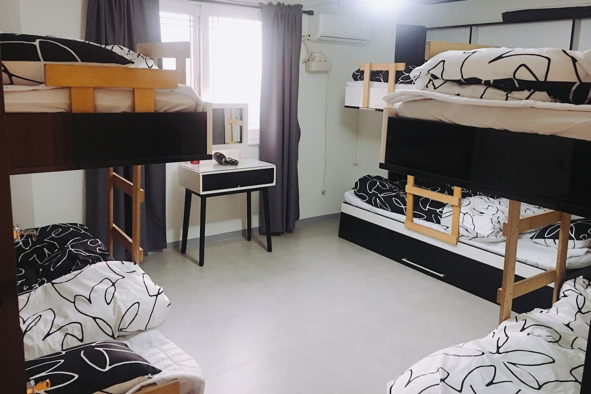 A dormitory room with bunk beds, a desk, and a chair.