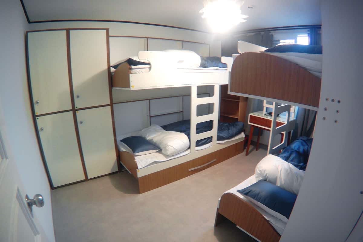 A bunk bed room with a wardrobe and a desk.