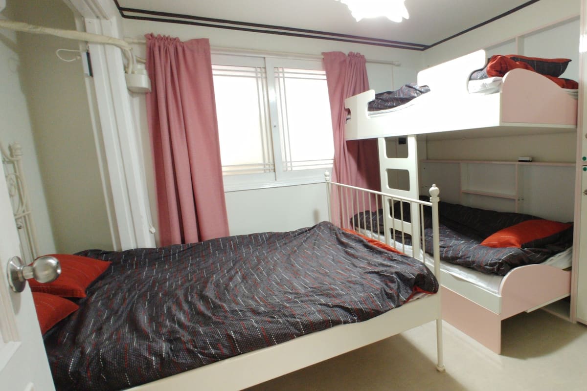 A bunk bed room with a window, curtains, and a wardrobe.