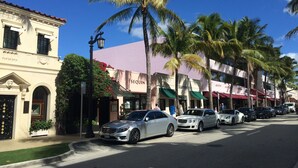 Une rue bordée de palmiers et où sont garées des voitures, dont une Bentley.