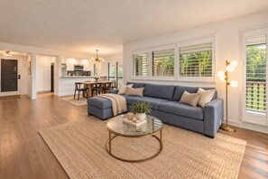 A spacious living room with a sectional sofa, a coffee table, and a dining area in the background.