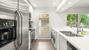 A modern kitchen with stainless steel appliances, a dishwasher, and a sink. - Restoration Hardware PGA National Condo w/ 180° Golf Course Views (Palm Beach Gardens)