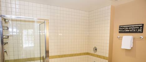 A bathroom with a glass-enclosed shower, a bathtub, and a toilet.