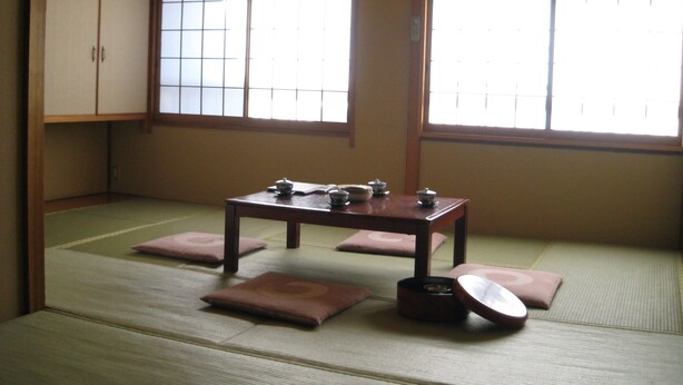 A traditional Japanese room with tatami flooring, a low table with tea sets, and sliding doors. - Nihonkan (Kyoto)