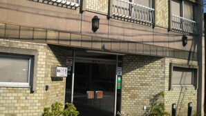A multi-story building with a brick facade, a covered entrance, and a small balcony with metal railings. - Nihonkan (Kyoto)