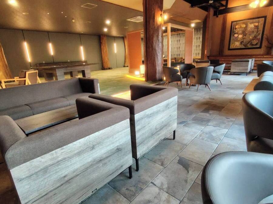 A modern lounge area with sofas and armchairs, a reception desk, and a large window.