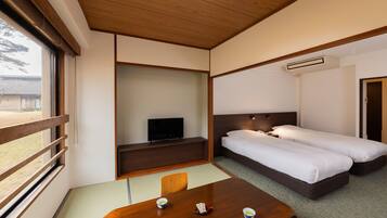 Habitación de hotel con techo de madera, un televisor en un estante, dos camas, una mesa con tazas y vistas al exterior.