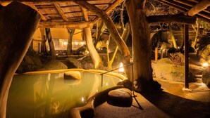 Un área de aguas termales con construcciones de madera y una piscina.