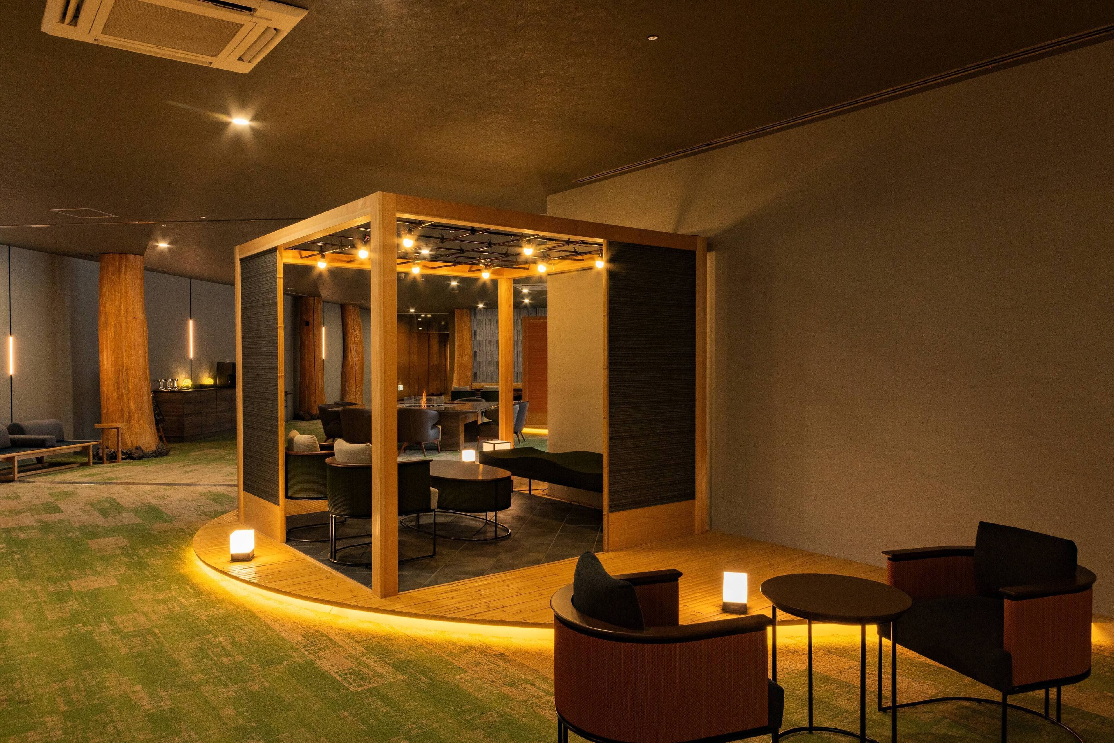 A modern lounge area with a central seating arrangement, a small table, and a coffee machine.