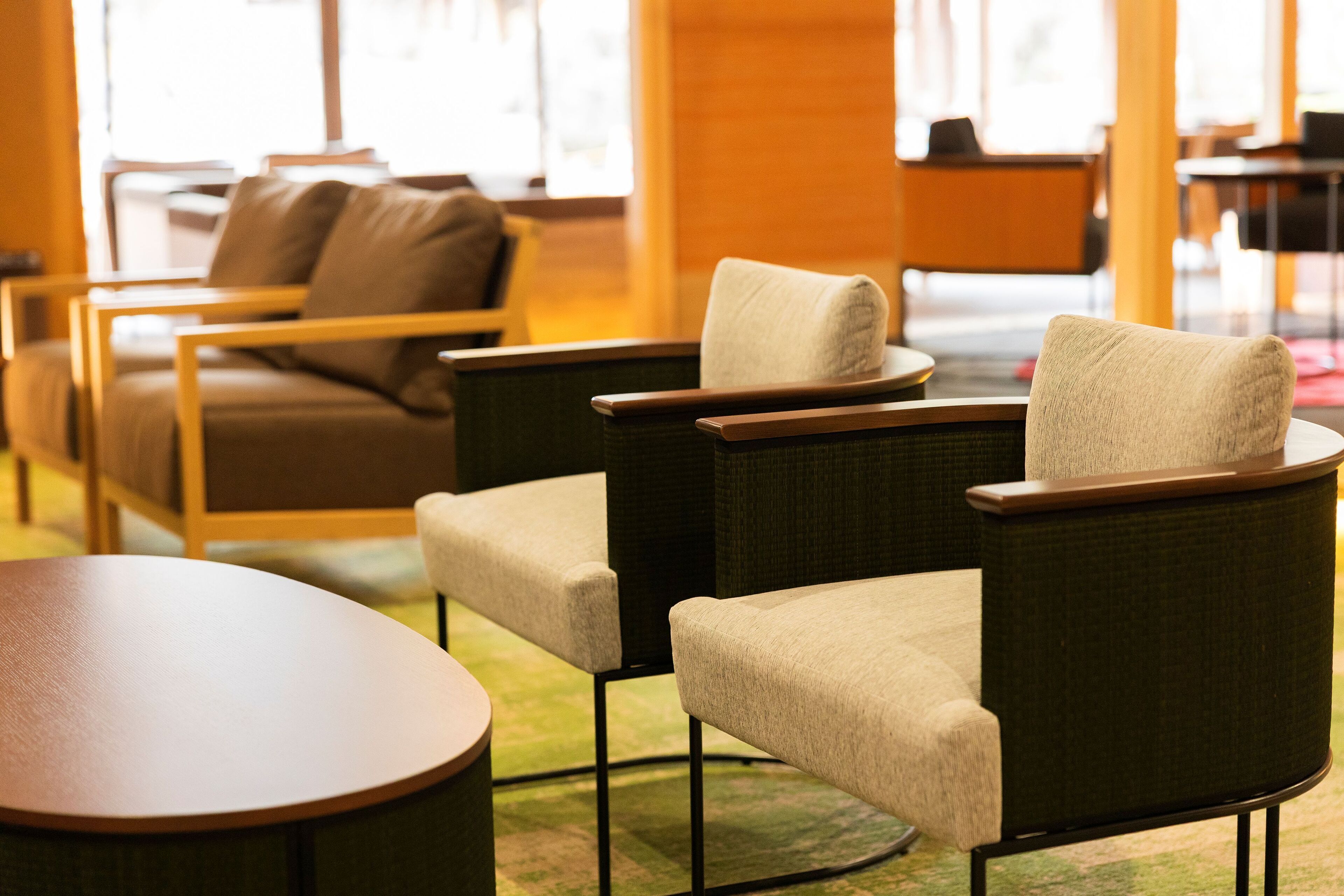 A seating area with cushioned chairs and a round table, featuring a wooden frame and a green carpet.