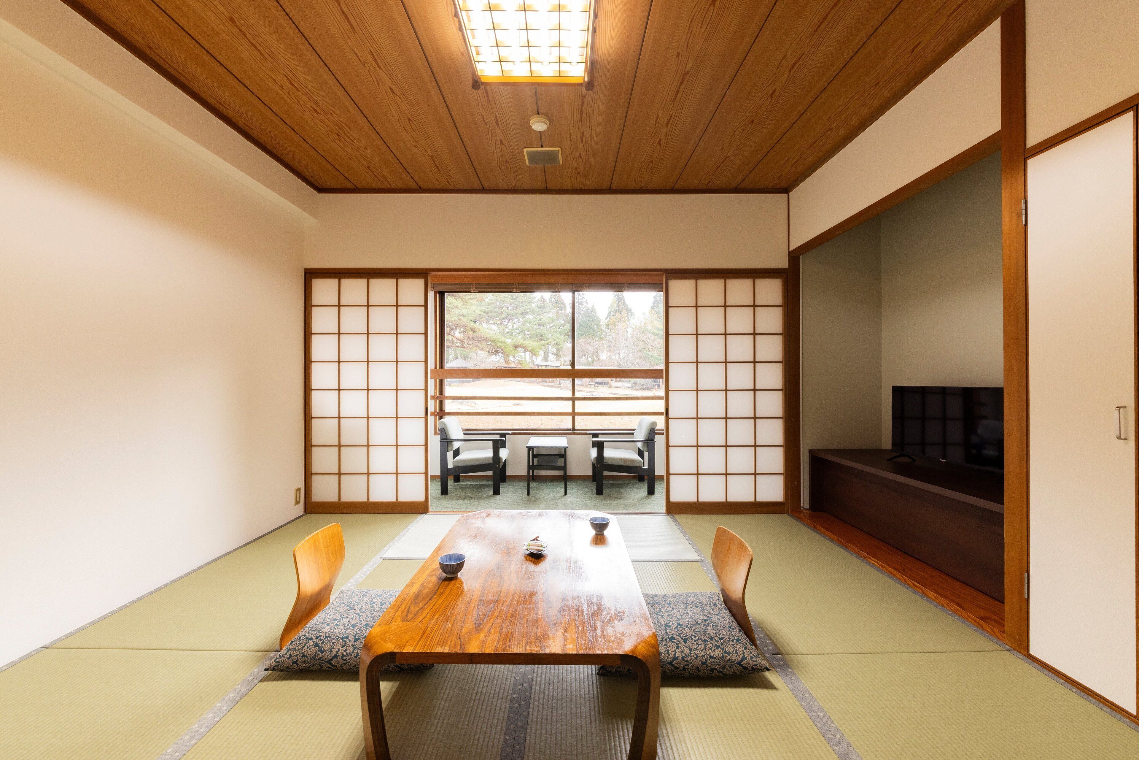 A traditional Japanese room with tatami flooring, a wooden table, and a sliding door.