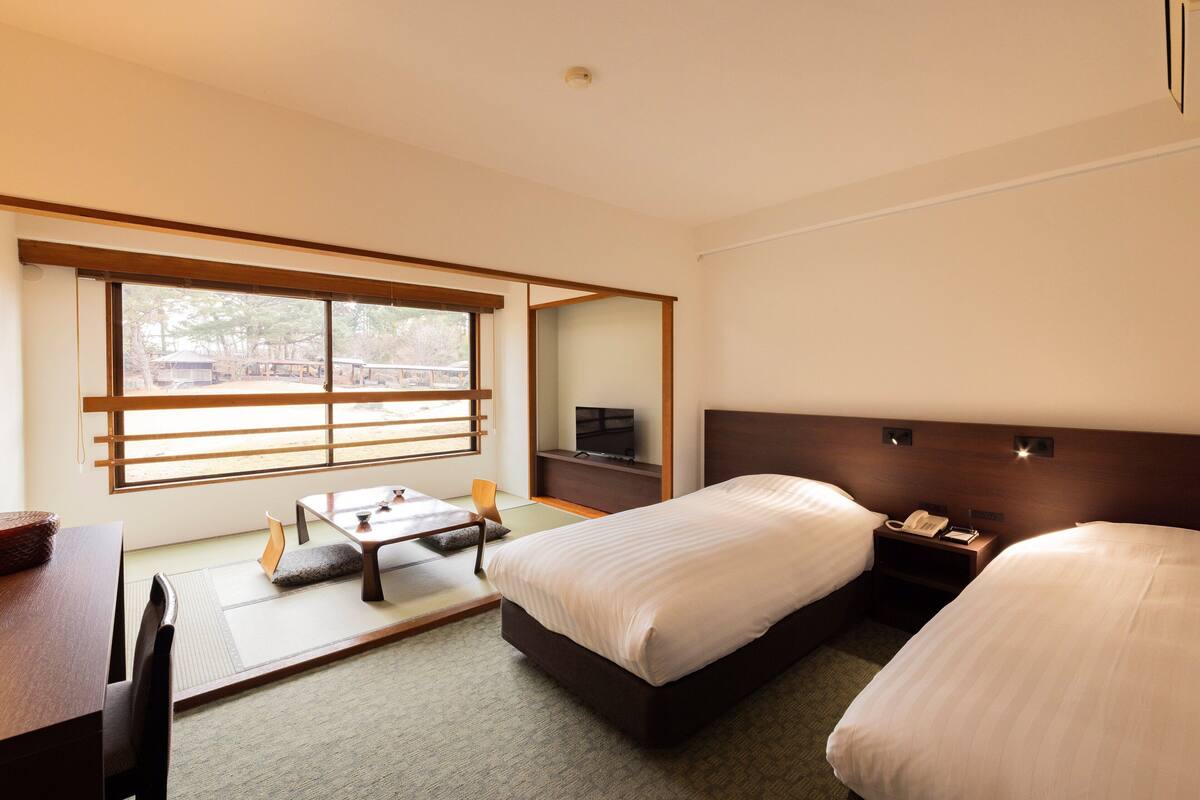 Une chambre d’hôtel avec une grande fenêtre, un lit, un bureau et un téléviseur.