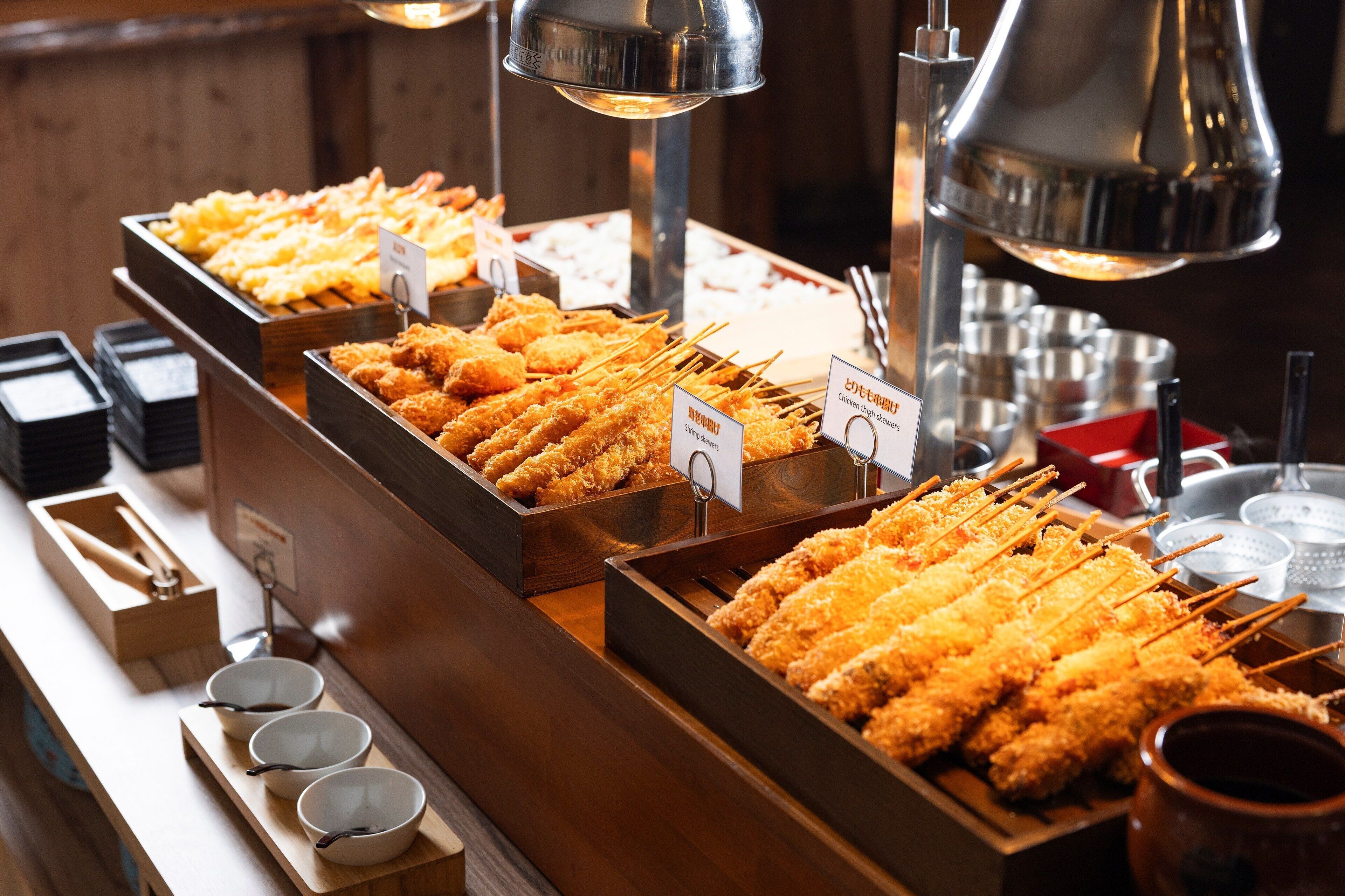A buffet with various fried items and bowls of sauce.