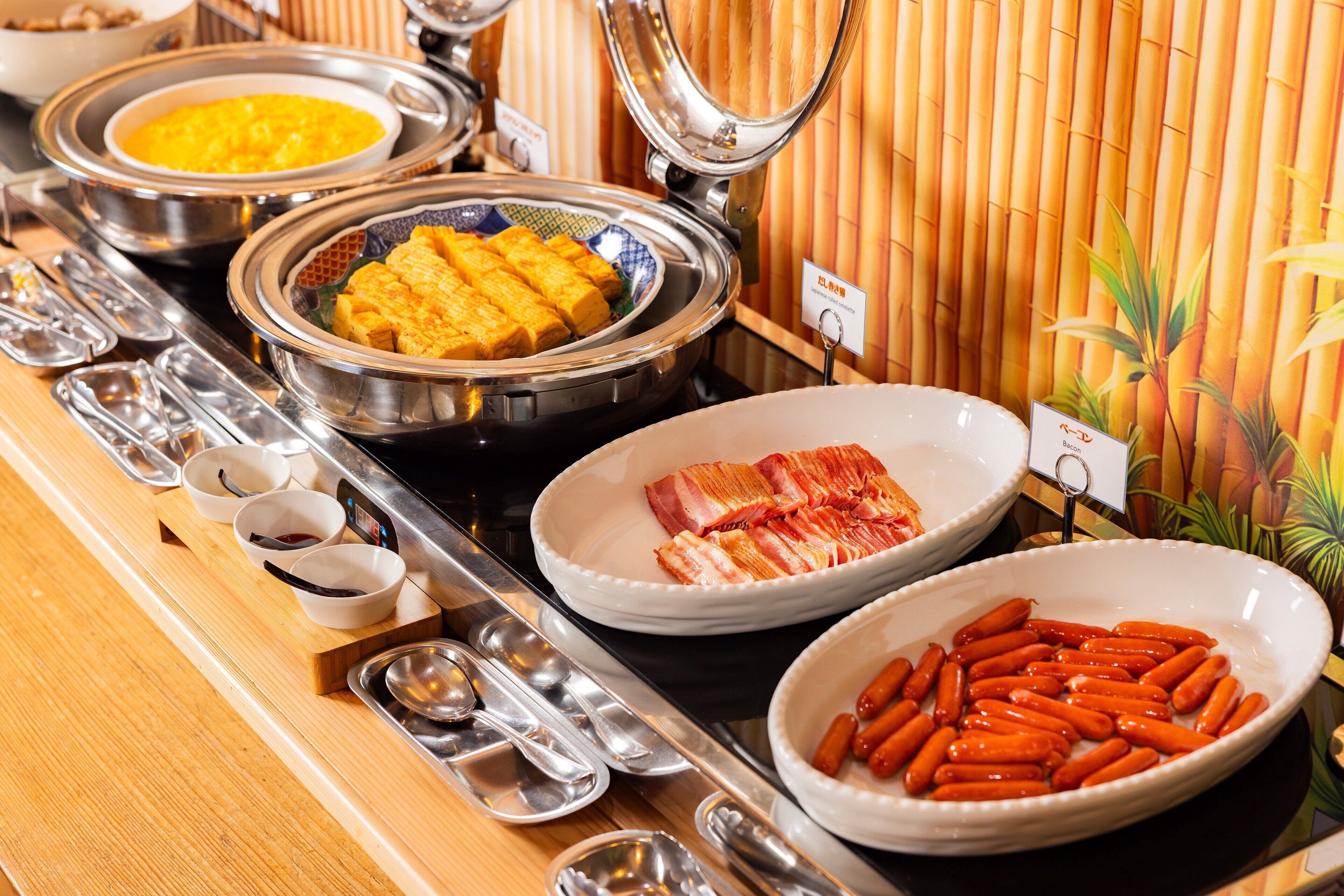 A buffet with various dishes including tofu, bacon, and sausages.
