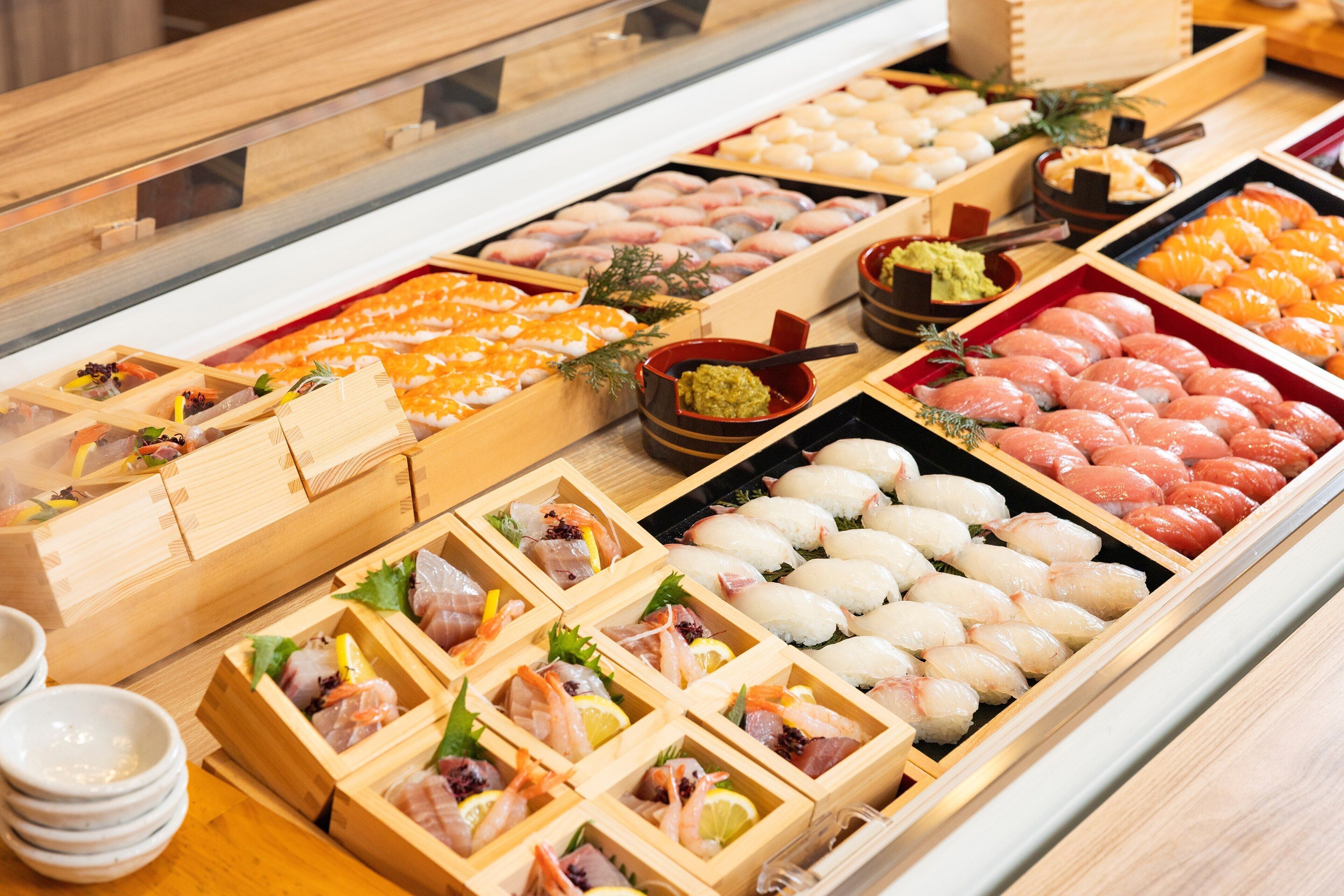 A variety of sushi displayed in wooden boxes and trays.