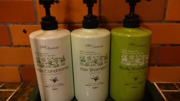 Three bottles of DHc Amenity hair and body care products on a shelf.