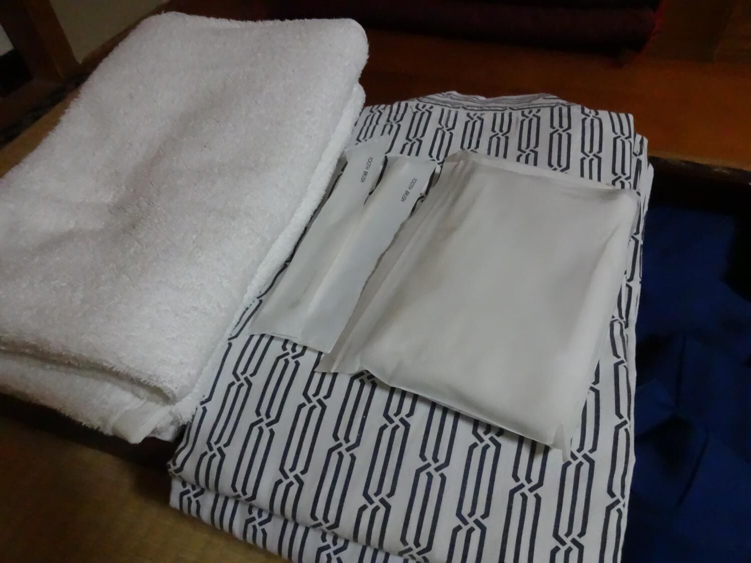 A neatly folded white towel and a patterned garment on a wooden floor.