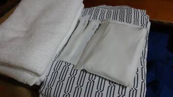 A neatly folded white towel and a patterned garment on a wooden floor.