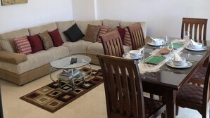 Ein modernes Wohnzimmer mit einer Couch, einem Esstisch, Stühlen und Deckenventilatoren.