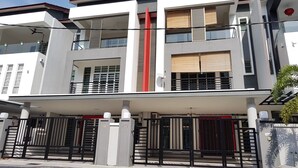 Un edificio moderno de dos pisos con techo plano, ventanas grandes y entrada protegida por una reja.
