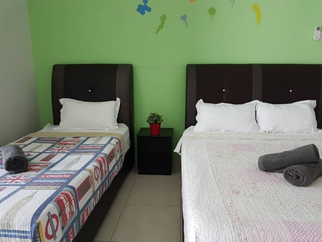 A room with two beds, each with a different style of bedding. There is a small table with a plant between the beds.