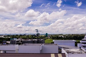Blick auf eine Stadtlandschaft mit einer Brücke in der Ferne, Gebäuden und einem bewölkten Himmel.