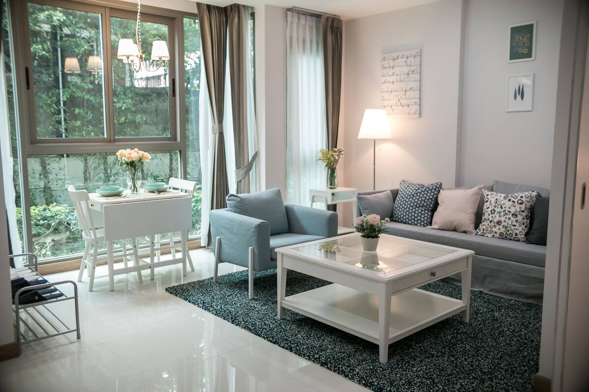 A modern living room with a white coffee table, grey sofa, and a dining table with chairs.