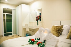 Ein modernes Hotelzimmer mit Bett, Schreibtisch, Stuhl und einem großen Spiegel.