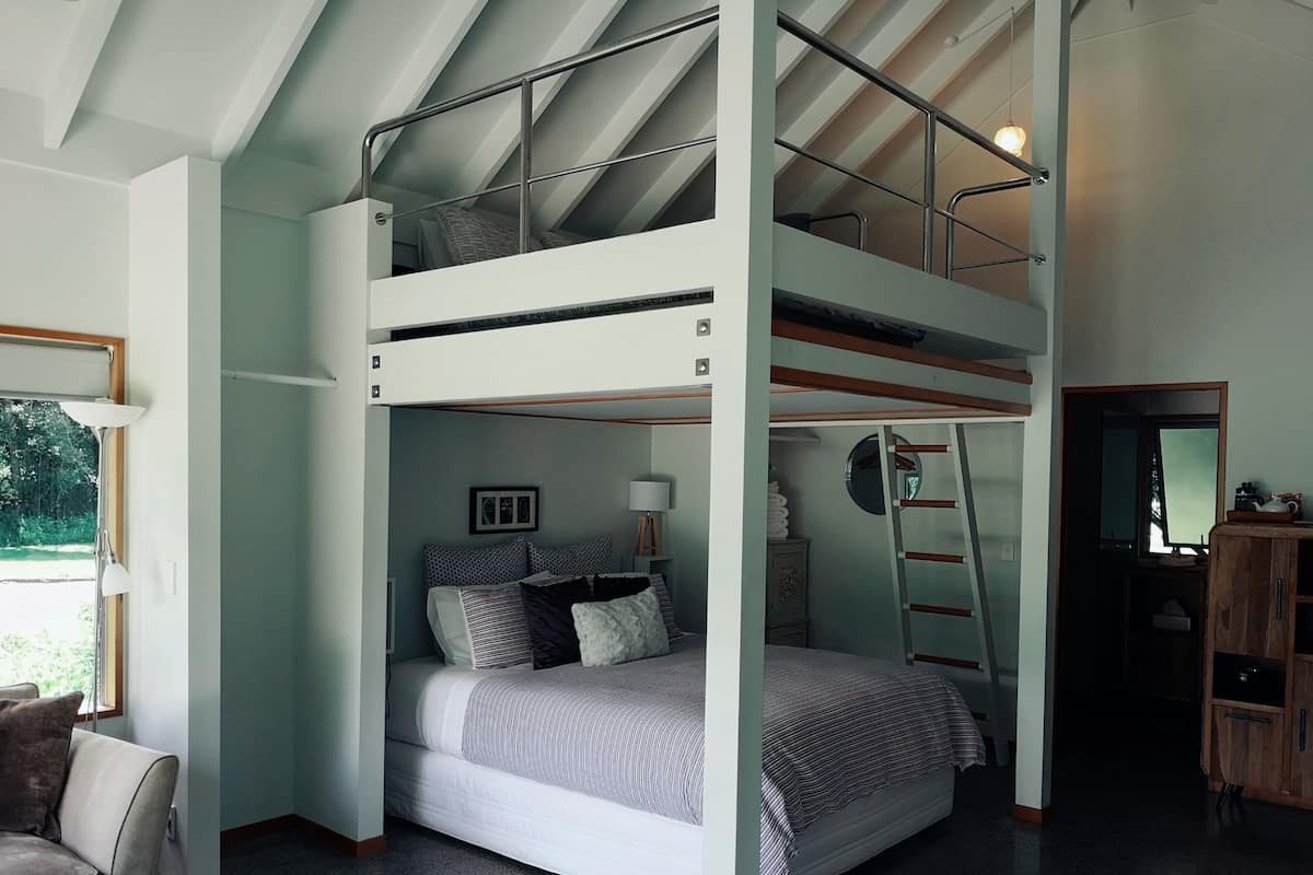 A bunk bed room with a ladder, a desk, and a mirror.