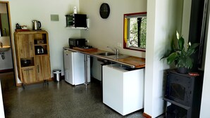 A compact kitchen with a refrigerator, microwave, sink, and a small stove. - The Waterlily Gardens (Waihi)