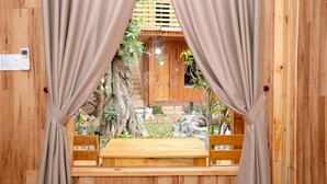 A wooden cabin with a wooden bench and curtains in front of a window.