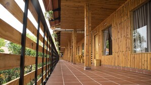 A covered wooden corridor with tiled flooring, wooden pillars, and hanging plants.